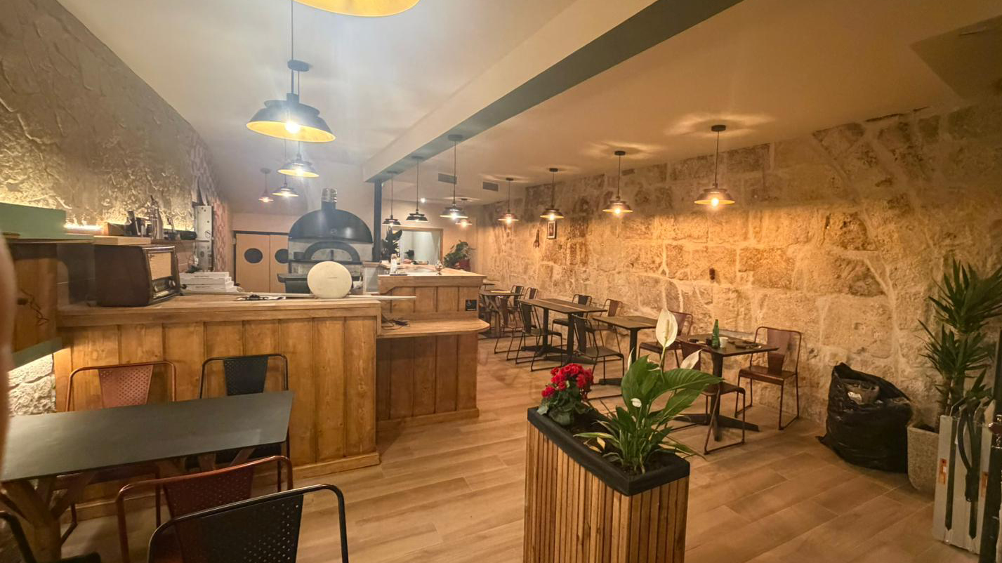 Intérieur d'Il Forno, pizzeria Béziers centre : four à bois et mur en pierre apparente